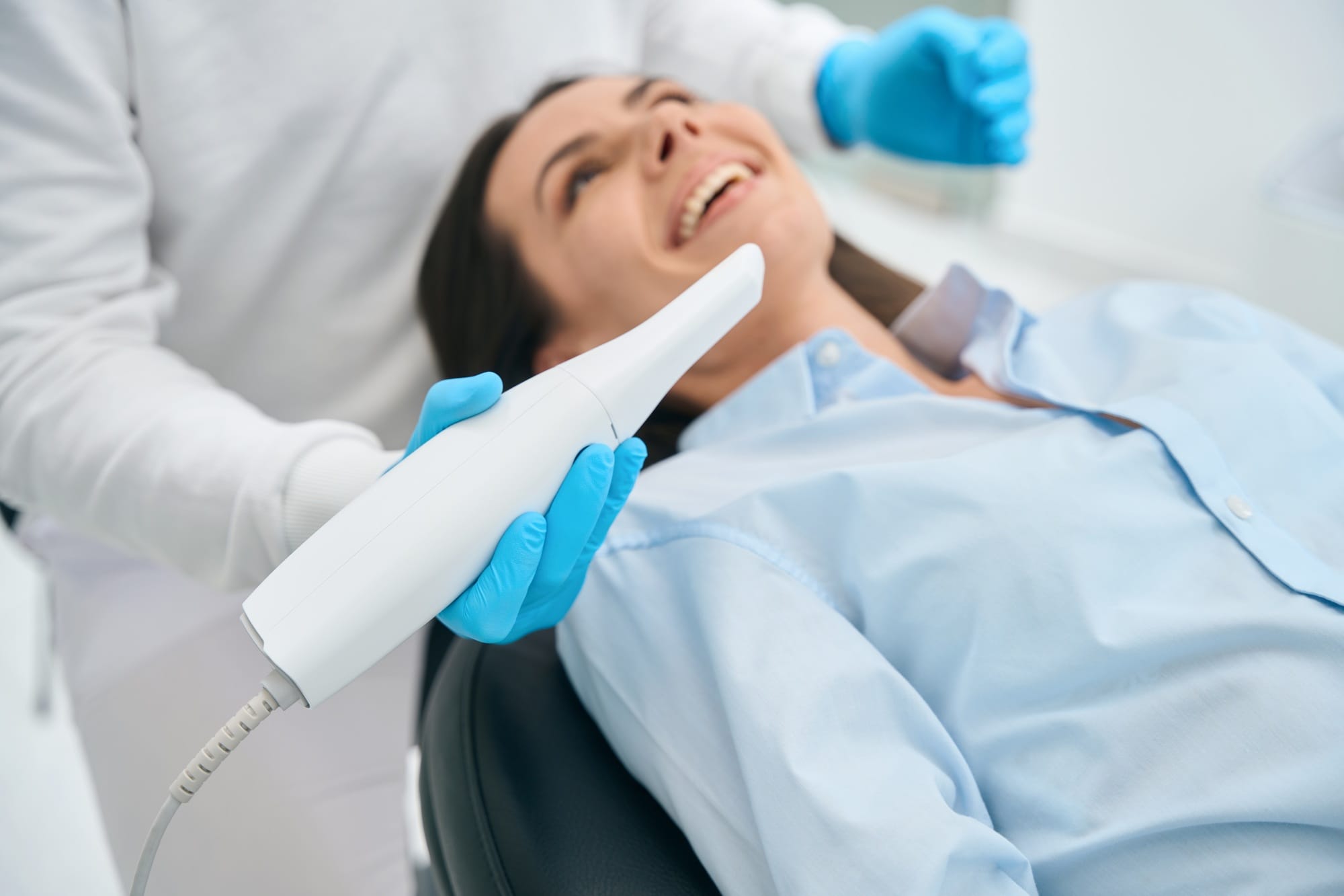 Stomatologist in uniform taking intraoral camera to examine mouth inside
