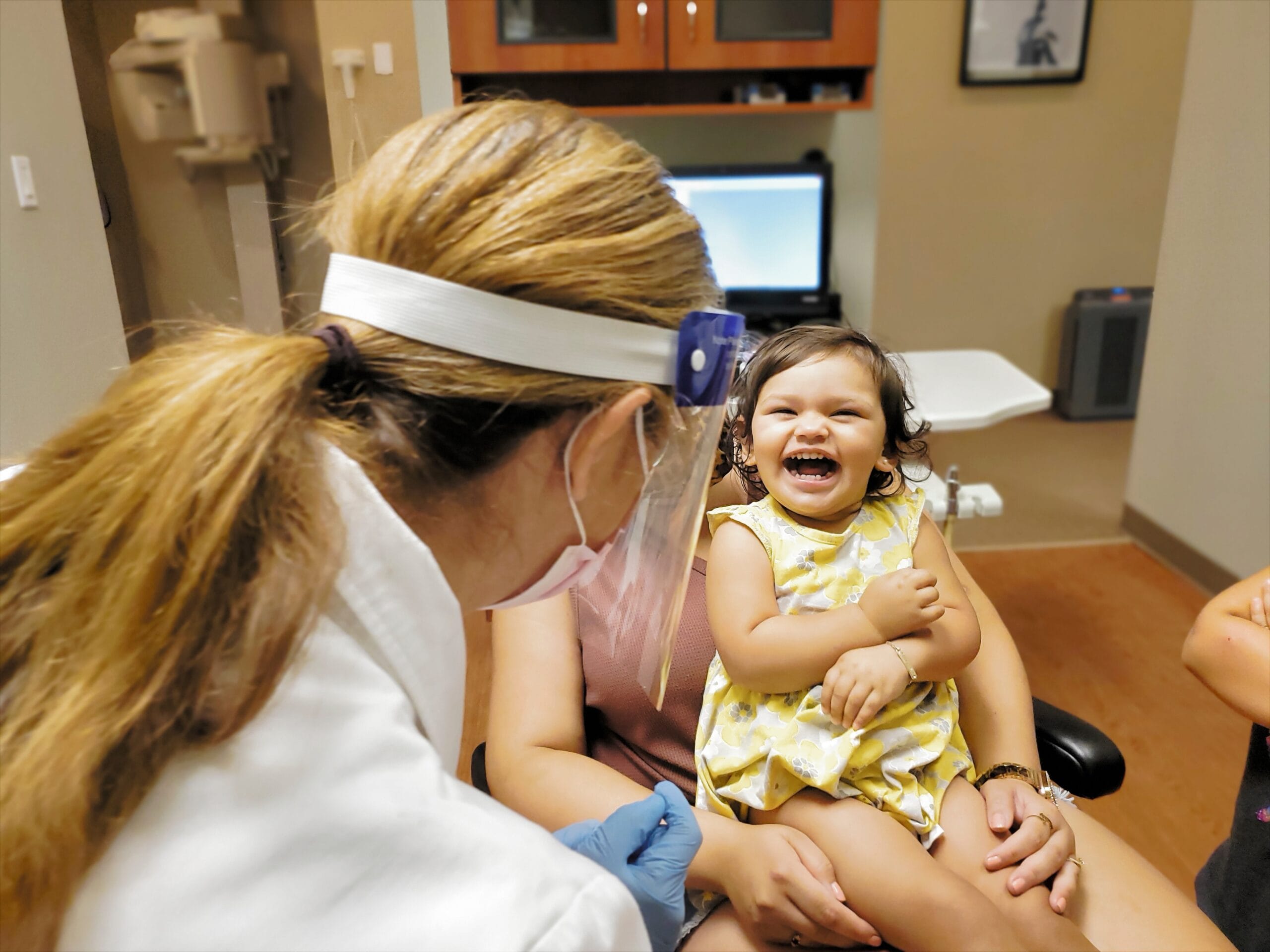 a-toddler-girl-laughs-while-sitting-on-her-mom-2024-12-05-04-24-43-utc Dental team examines the oral health and provides advice on oral care for children.