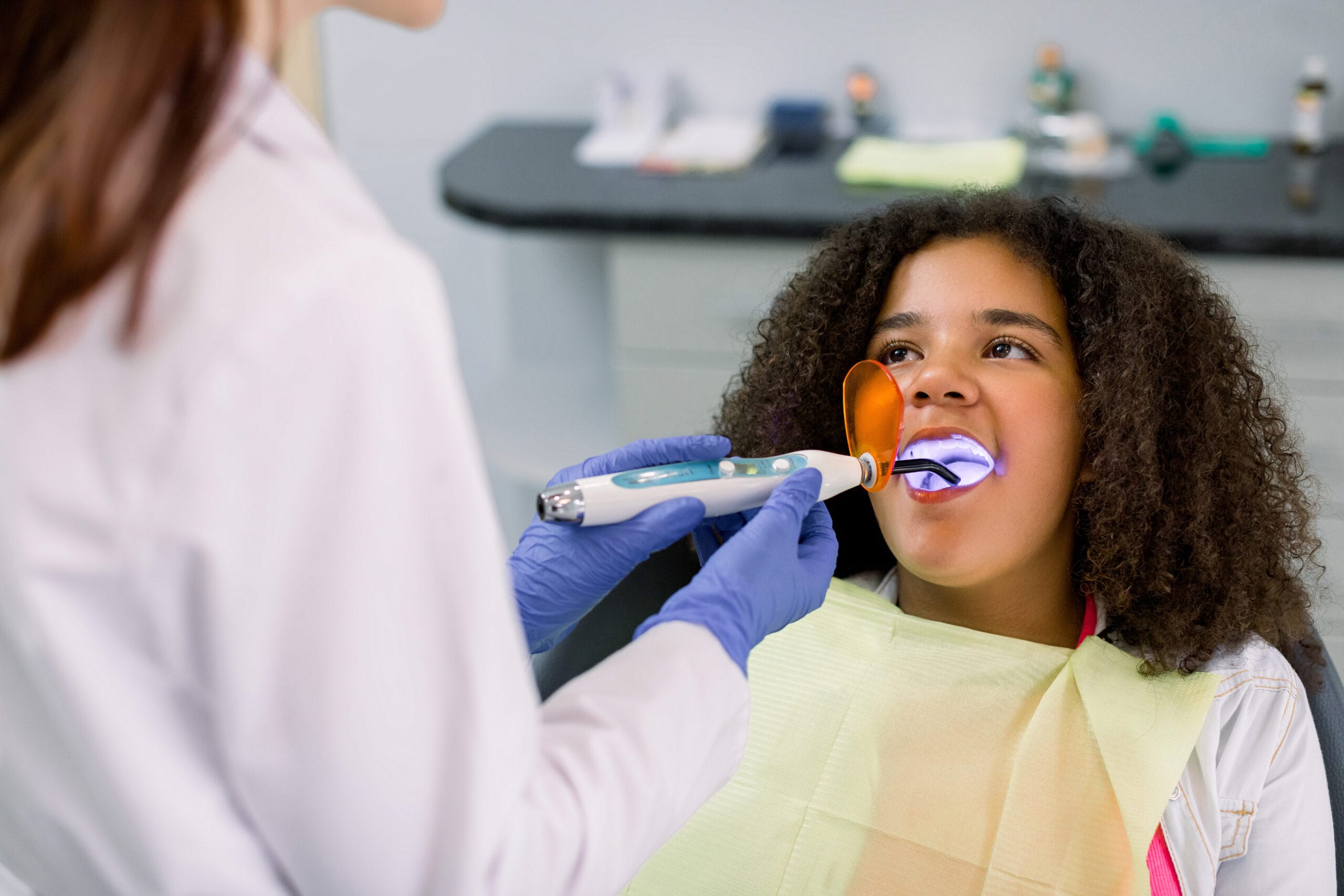 Dentist applying dental sealant on teeth of teenage girl