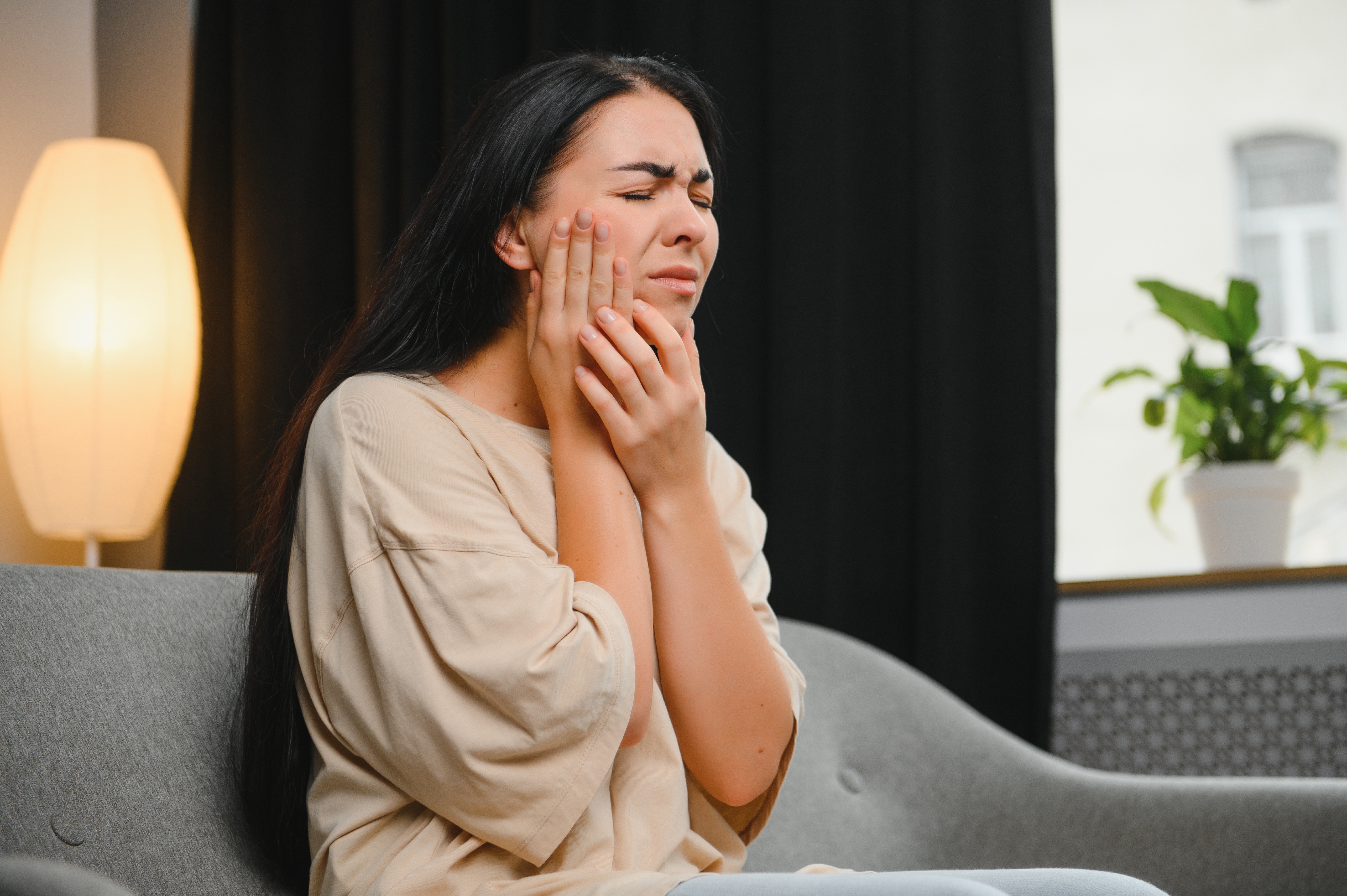 Attractive young woman suffering from toothache. Woman holding her cheek in pain. soft tissue laser treatment